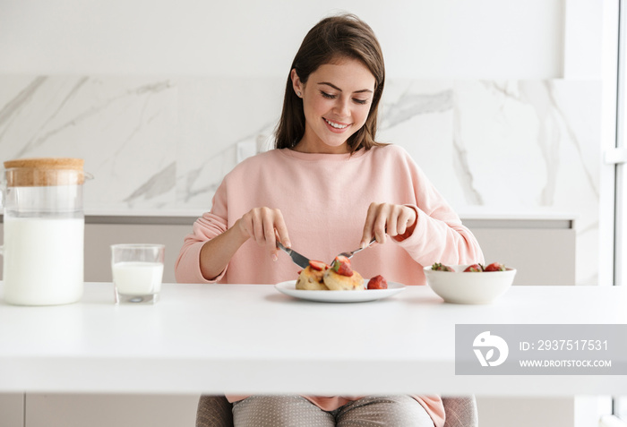 Beautiful smiling young girl having tasty healthy breakfast