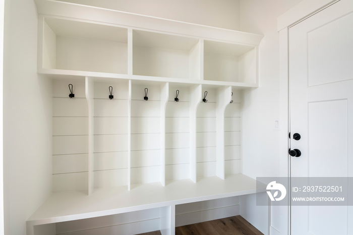 Interior of a white mudroom with white garage door and wooden flooring