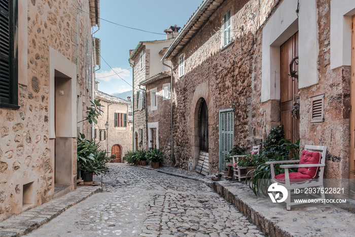 empty narrow cobbled street in small spanish village with typical houses on both sides