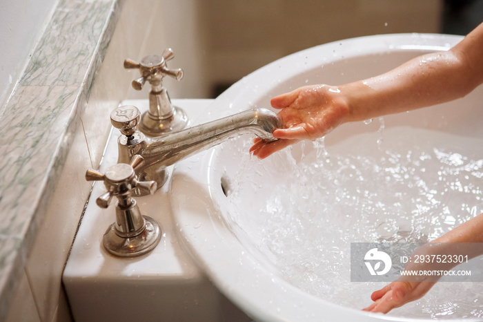 Cropped image of girl washing hands in sink at home