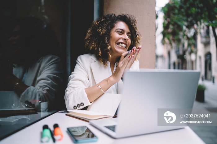 Cheerful female graphic designer feeling delight and happiness while doing remote work on laptop com