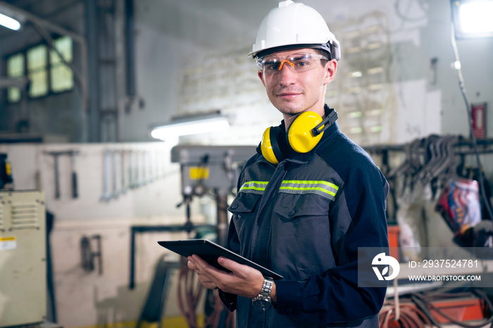 Young factory worker using adept tablet computer in a workshop building . Industrial technology and 