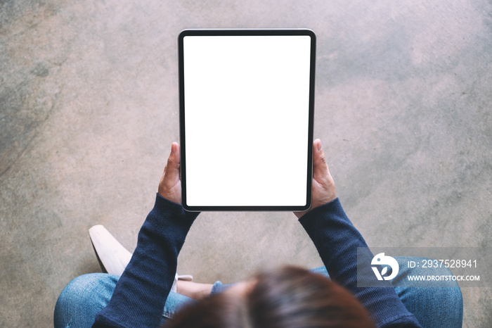 Top view mockup image of a woman holding black tablet pc with blank white screen while sitting on th