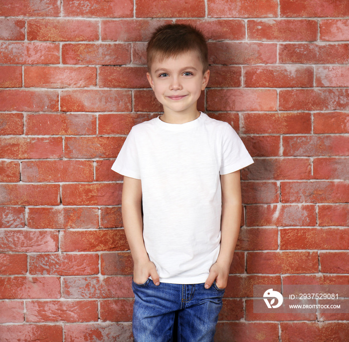 Cute boy in white T-shirt on brick wall background