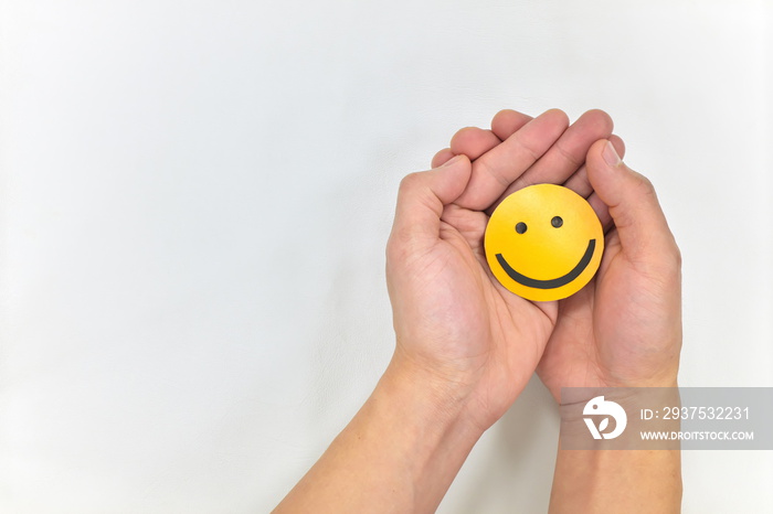 Two hands hugging a yellow smiley face on white background. Happy together and share happiness to ot