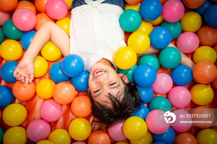 Happy asian girl playing in colorful balls pool