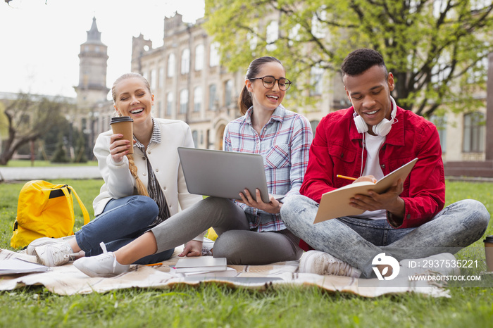 Feeling amazing. Hard-working students feeling amazing while drinking coffee sitting in the park nea