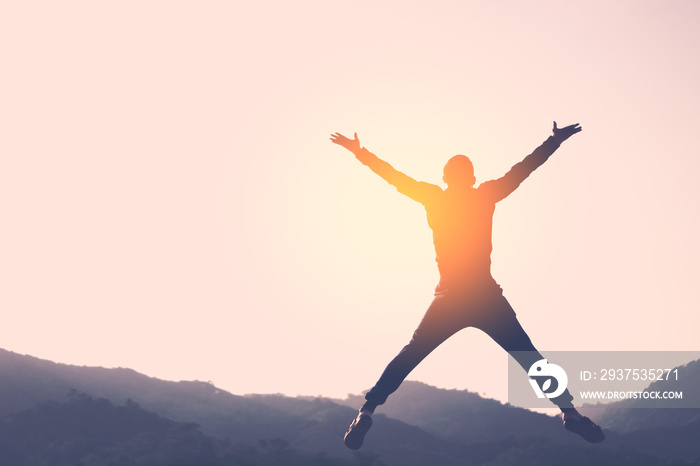 Happy man jumping at top of mountain with sunset sky abstract background.