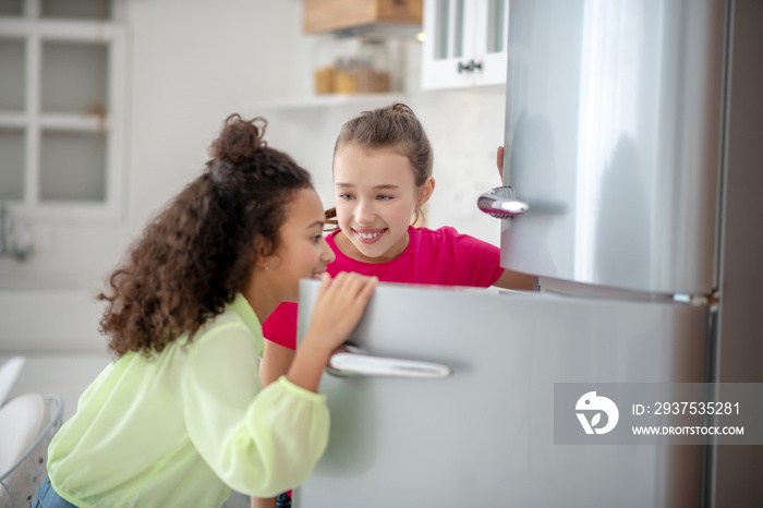 Two girls opening the fridge feeling excited