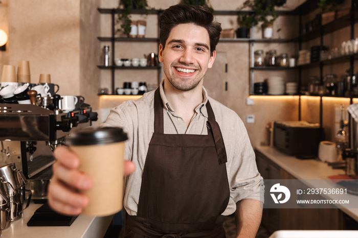 Handsome happy coffee man posing in cafe bar working indoors holding coffee cup.