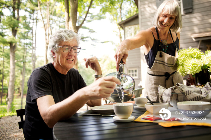 Smiling woman pouring water into coffee cup