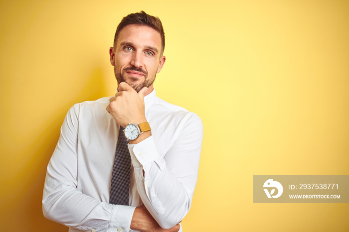 Young handsome business man wearing elegant white shirt over yellow isolated background looking conf