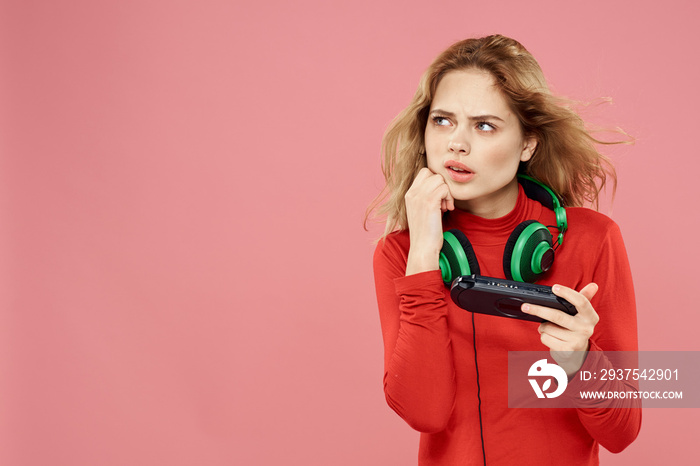 Woman with mobile set-top box headphones playing lifestyle pink background red jacket