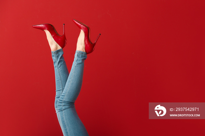 Legs of young woman in high-heeled shoes on color background