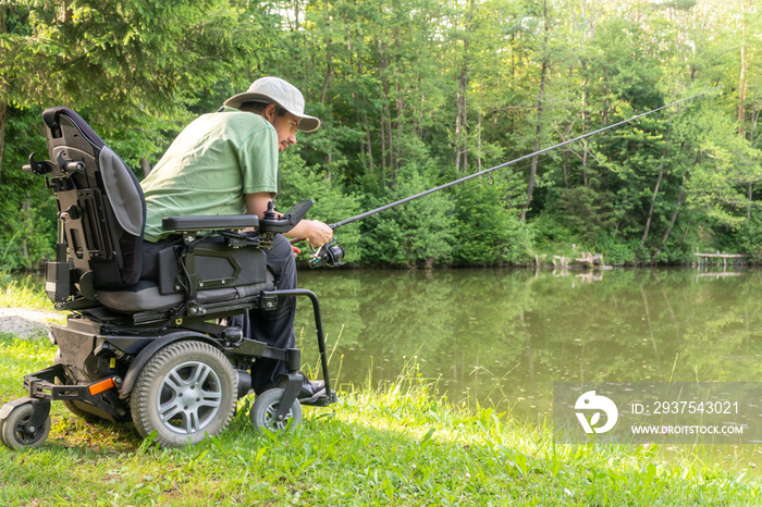 Happy man in a electric wheelchair waiting to catch a fish at the beautiful pond in natue on a sunny