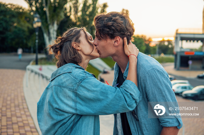 Lovely young hipster couple dating during summer sunset. they wear jeans clothes. they are kissing