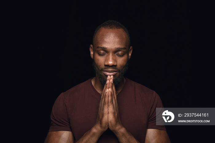 Close up portrait of young man isolated on black studio background. Photoshot of real emotions of ma