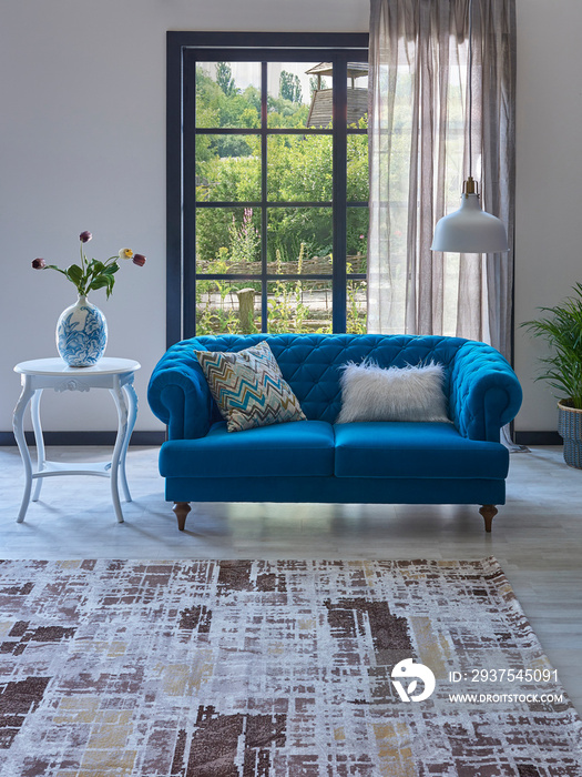 窗前蓝色经典沙发，地毯设计，植物、灯、花园的白色花瓶