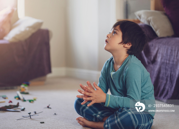 Happy kid sitting on floor clapping hands while watching cartoon onTV in living room, Cheerful child