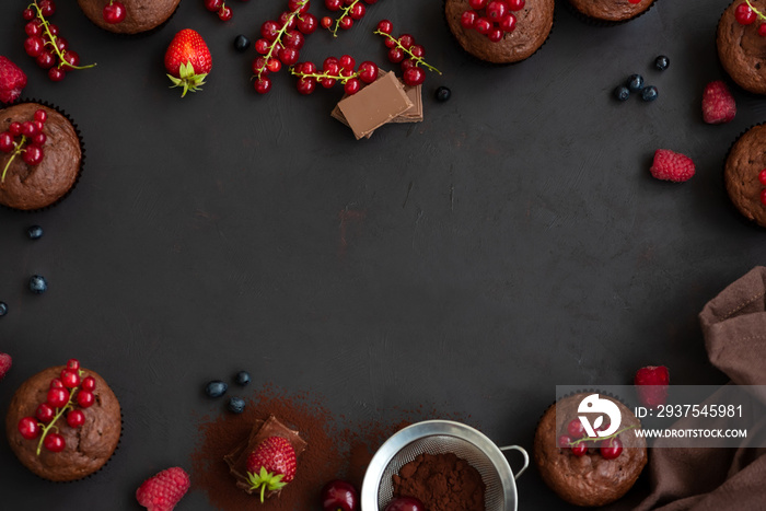 Frame with chocolate muffins, chocolate bars, cocoa and berries on dark wooden background. Top view.