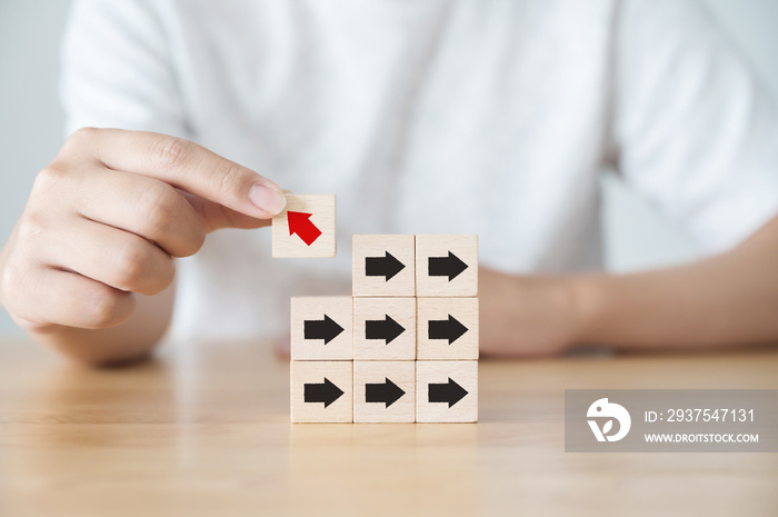 Hand holding wooden block with red arrow facing the opposite direction black arrows, Unique, Think d