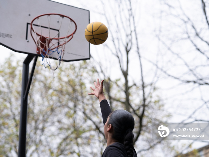 Teenage girl playing basketball outdoors