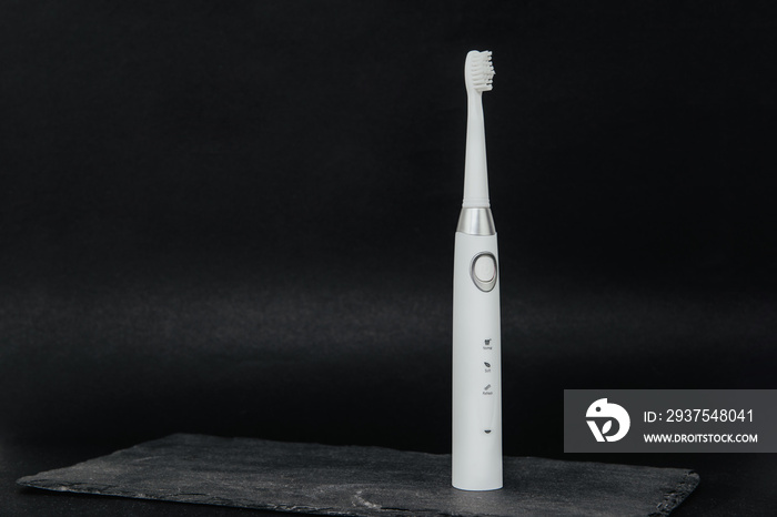 White sonic toothbrush on a dark stone background. Medical and dental concept. Caring for teeth, mod