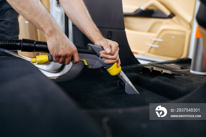 Worker cleans car interior with vacuum cleaner