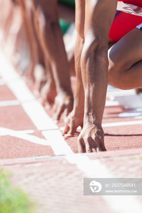 Male track and field sprinters ready at starting line