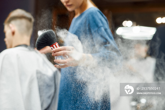 Close up shot of a professional barber girl using hair powder while working in the modern barbershop