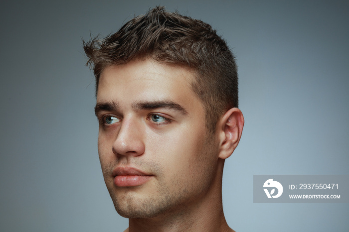 Portrait of shirtless young man isolated on grey studio background. Caucasian healthy male model loo