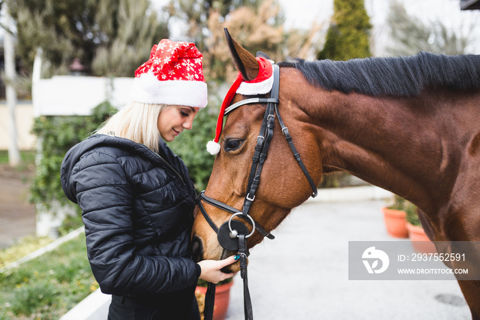 美丽的年轻女子在寒假与马一起享受。
