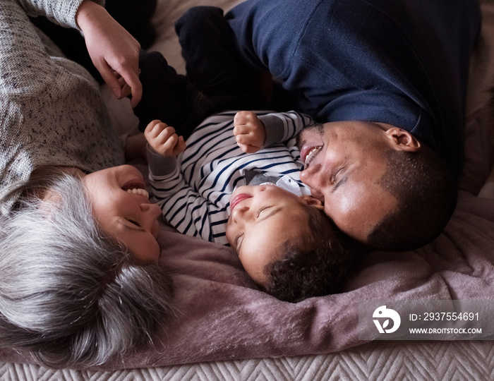 High angle view of happy parents with cute son relaxing on bed at home