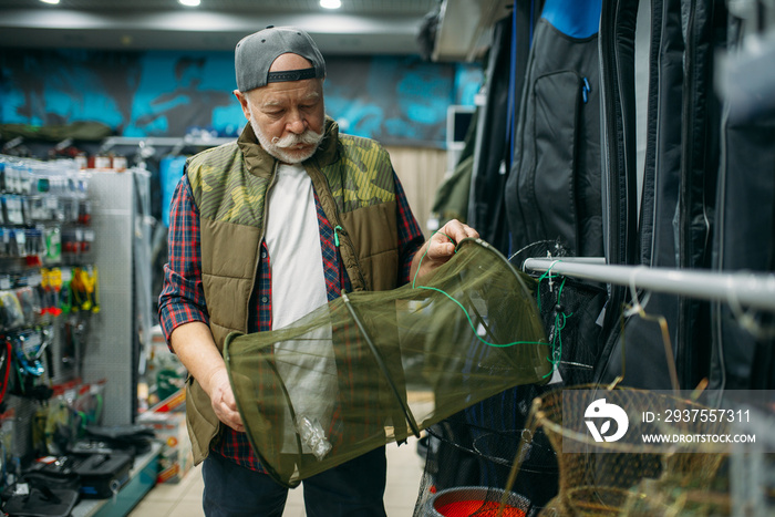 Male angler choosing net in fishing shop