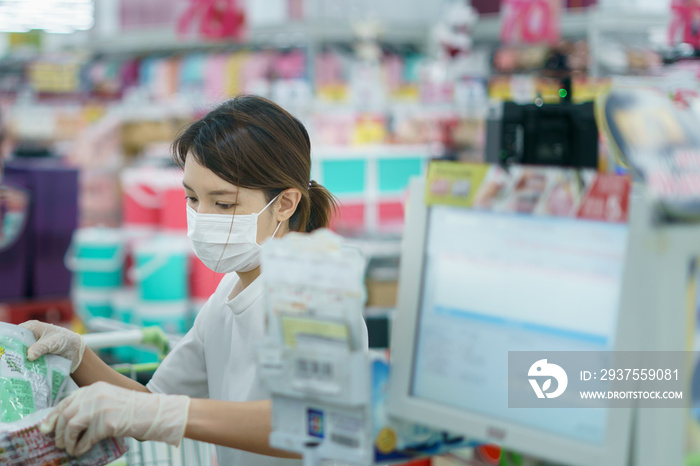 Woman protects herself from corona infection with surgical mask and gloves at cashier scanning groce