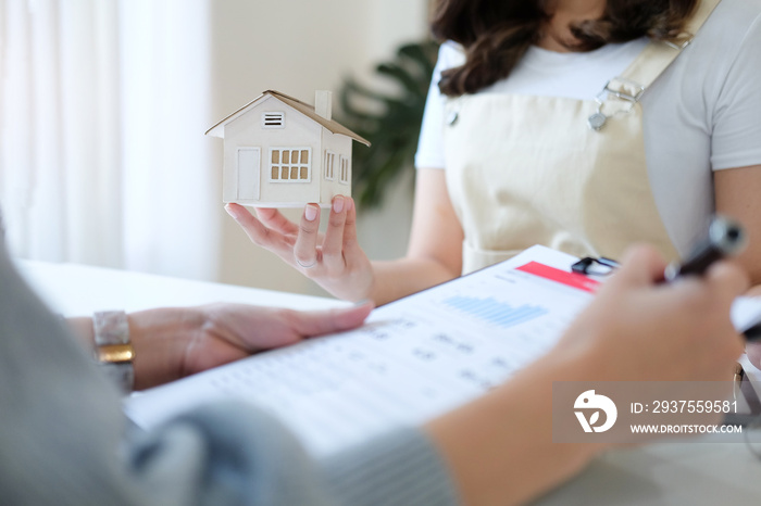 Young woman signing financial contract with real estate agent.