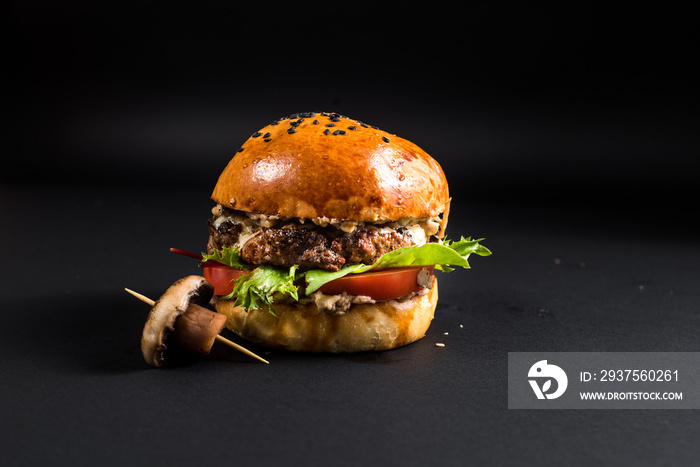 Tasty burger with grilled meat and mushroom on the black background