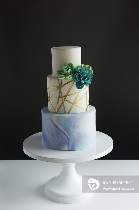 大理石、金色、几何设计和可食用多汁的三层现代婚礼蛋糕。时尚