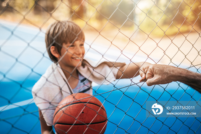 Grandfather and his grandson enjoying together on basketball court.