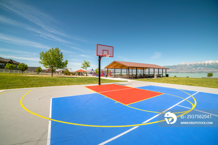 Outdoor basketball court with a picnic pavilion and playground in the background