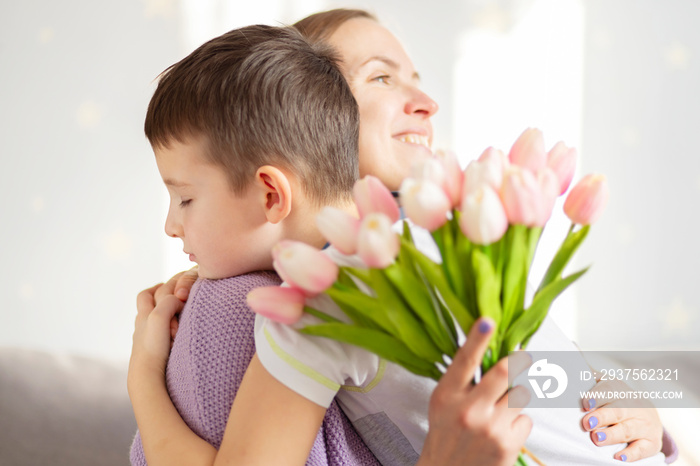 A cute son giving his mother a bouquet of tulips congratulating her on mothers day while celebratin