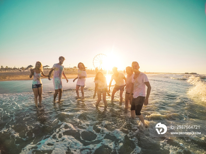 Happy friends having fun on the beach at sunset - Young people playing inside sea water outdoor in s