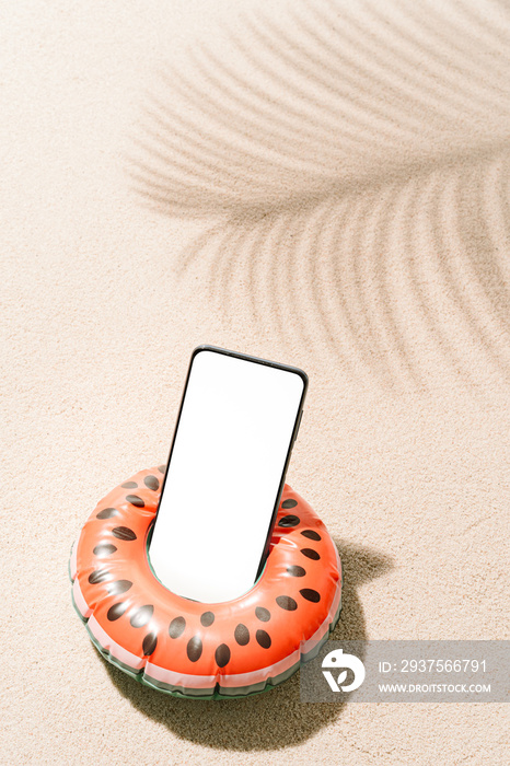 在有椰子阴影的热带海滩沙滩上，用手机做成充气西瓜形状