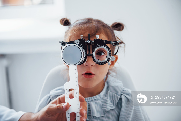 Little girl in eyewear in ophthalmology clinic have test of vision