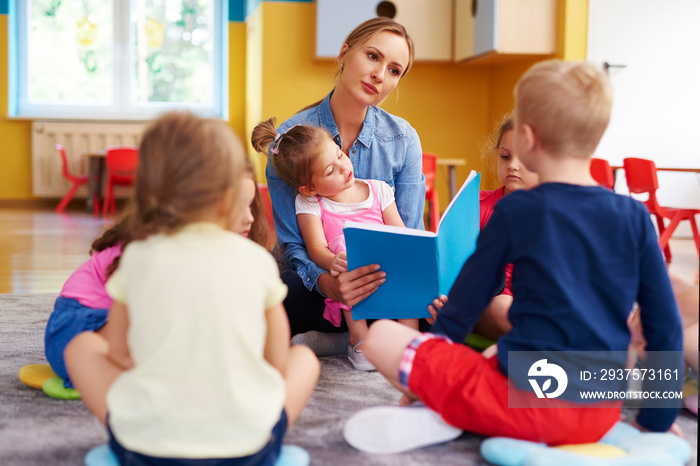 Preschool teacher is reading a book