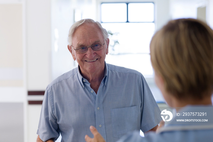 Smiling senior patient talking with nurse in clinic