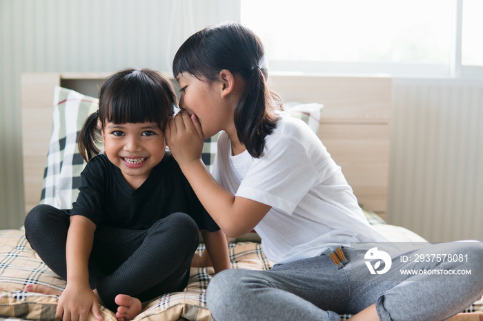 happy little Asian siblings sharing secrets