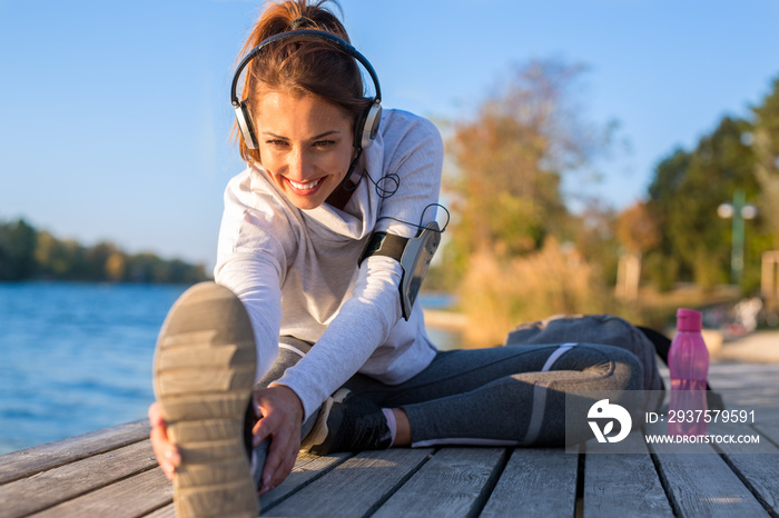 Beautiful young woman working out outside by the water