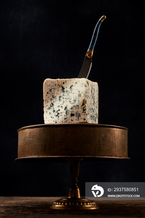 Block of blue mold cheese on dark background. Blue cheese dark rustic food photography.