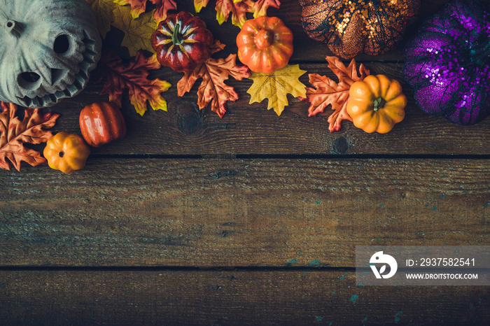 Creative autumn Halloween layout with various leaves and pumkins on dark wooden backgound. Flat lay.